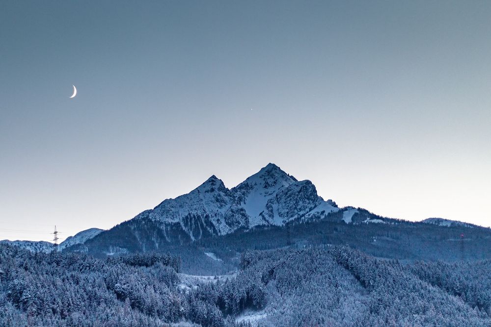 Wintery Nockspitze and the silhoutte of the moon with a peek of Jupiter above the peak